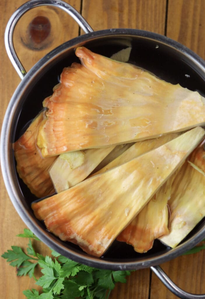 Pieces of chicken of the woods mushroom cooking in a pot of water before preparing the pie.